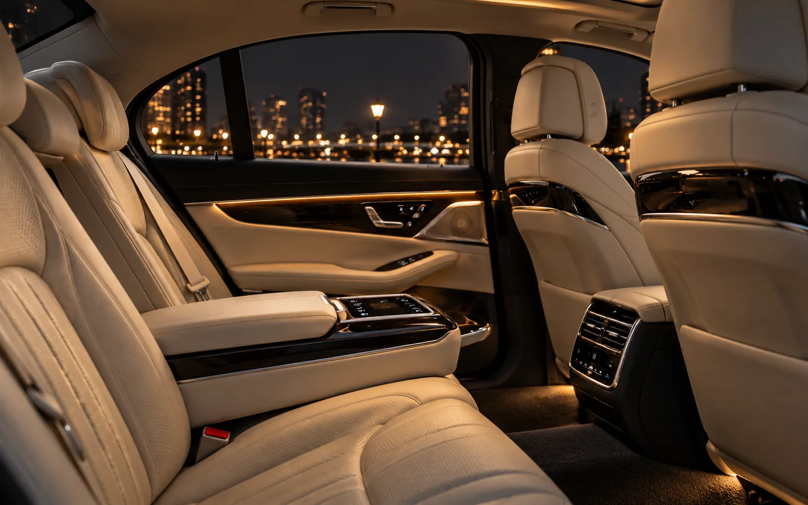 The rear cabin of an executive saloon at night, with quilted ivory leather seats, wood trim and soft ambient light